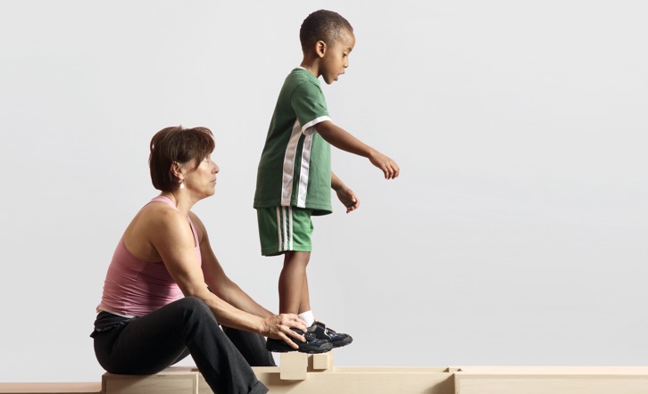 A physical therapist helps a boy with muscular dystrophy exercise.